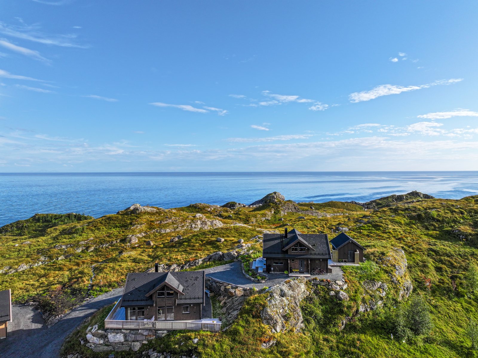 Dronefoto som viser begge hyttene med havet i bakgrunnen