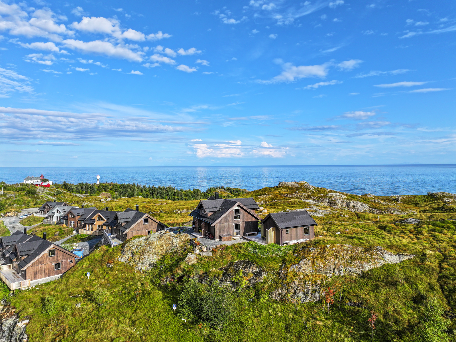 Luftfoto over hyttetunet med fyret og havet i bakgrunnen